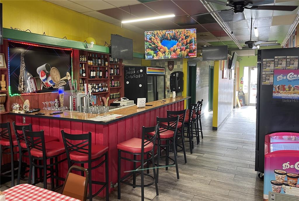 A bar area features red wooden paneling, black bar stools, and a television mounted above — 111 W HOWARD STREET, LIVE OAK, FL
