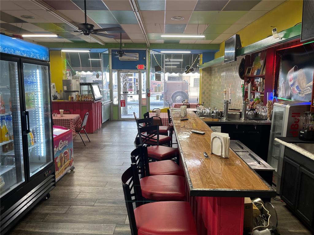A restaurant interior features a wooden bar with red stools, tiled flooring, and colorful ceiling panels — 111 W HOWARD STREET, LIVE OAK, FL
