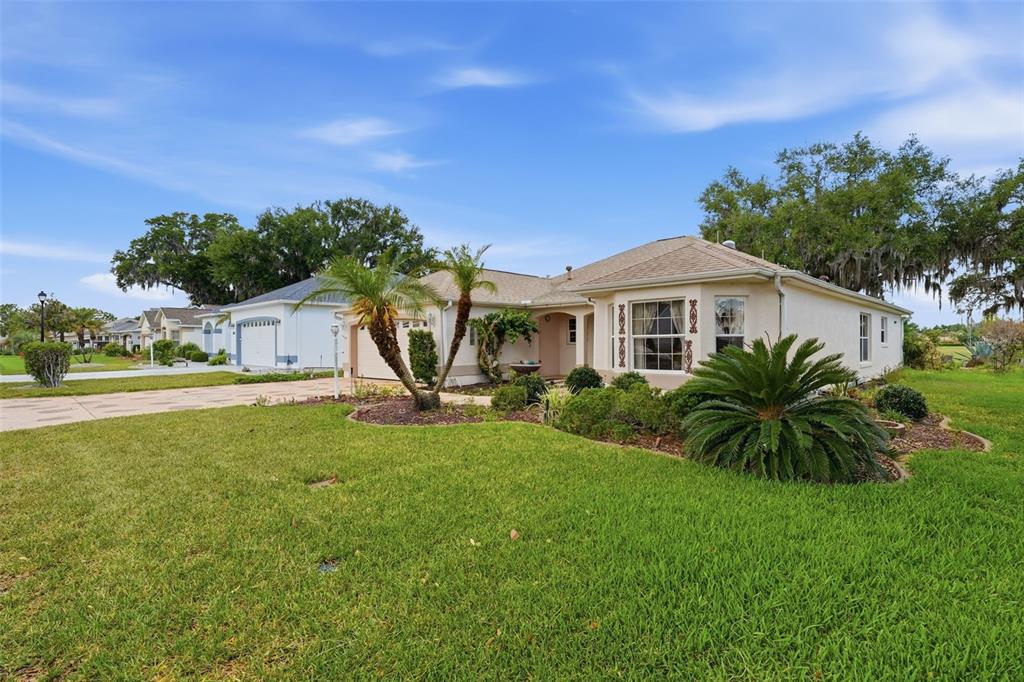 A single-story house with a beige stucco exterior, a shingled roof, and a landscaped front yard — 1344 AUGUSTINE DRIVE, THE VILLAGES, FL
