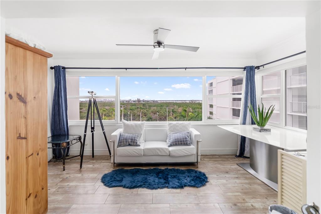 A sunroom features a white sofa, a telescope, a blue rug, and large windows — 1750 BENJAMIN FRANKLIN DRIVE UNIT 6G, SARASOTA, FL
