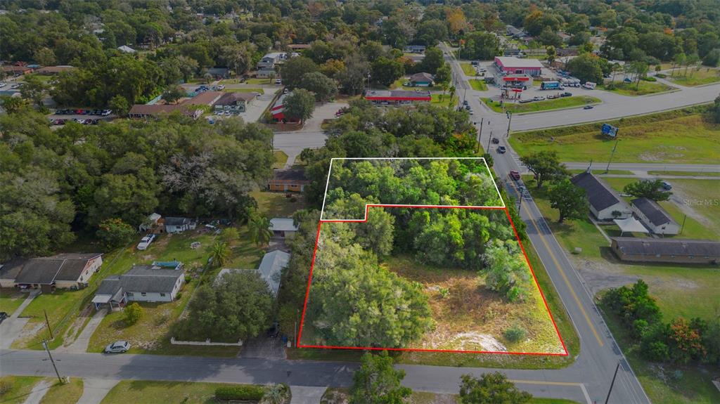 An aerial view shows a vacant, tree-covered lot outlined in red and white — 905 W BERESFORD AVENUE, DELAND, FL