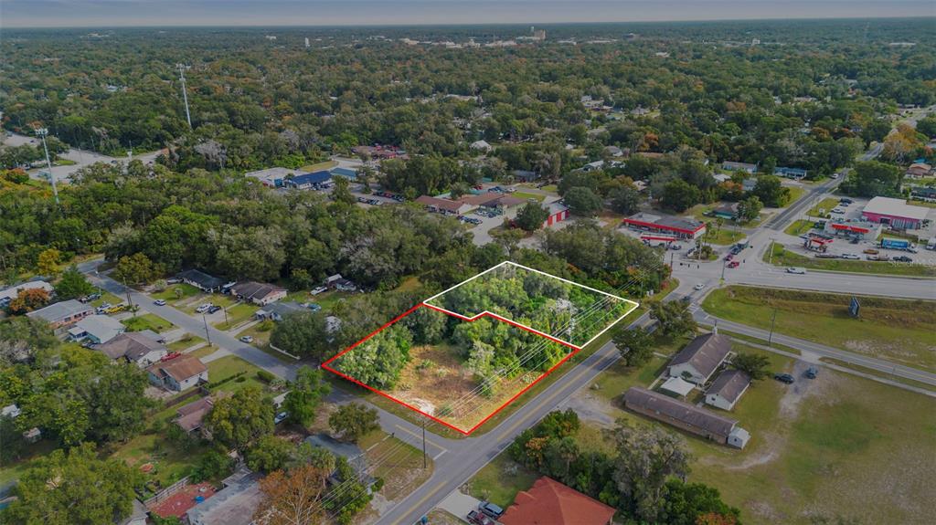An aerial view shows two adjacent wooded lots outlined in red and white near roads — 905 W BERESFORD AVENUE, DELAND, FL