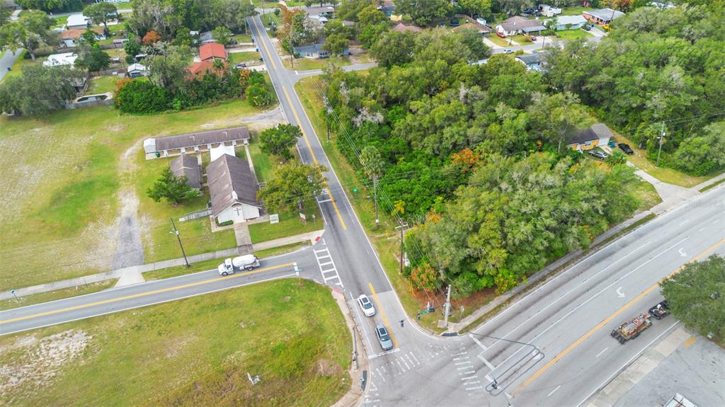 An aerial view shows a road intersection, a church building, and a wooded lot — 905 W BERESFORD AVENUE, DELAND, FL