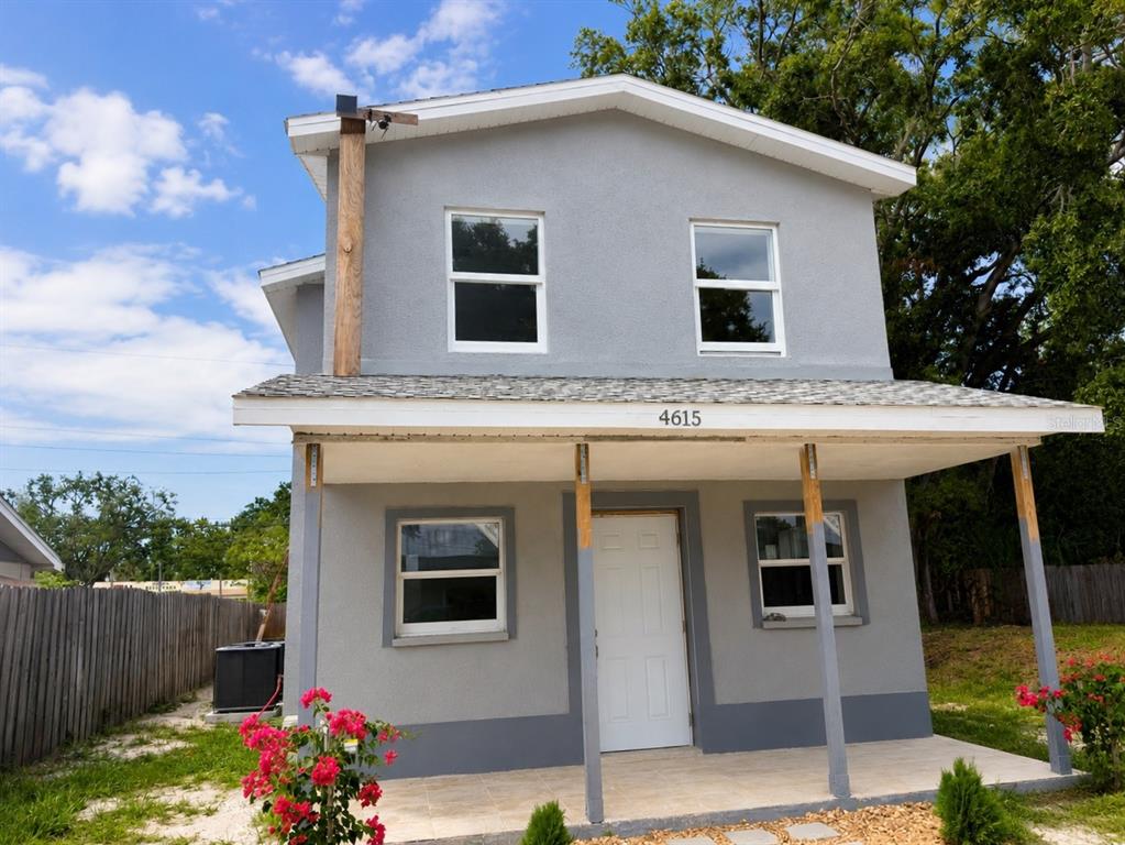 A two-story gray house with a front porch, white trim, and a fenced yard — 4615 AEGEAN AVENUE, HOLIDAY, FL