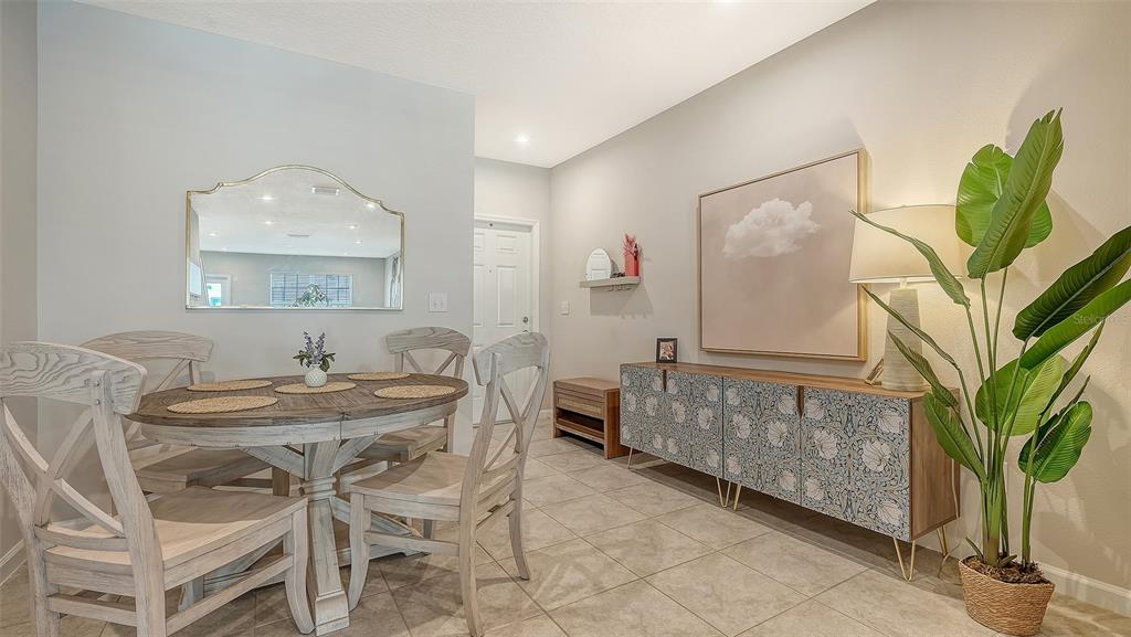 A dining area features a round wooden table, four chairs, a patterned sideboard, and a plant — 14147 CRIMSON AVENUE, BRADENTON, FL
