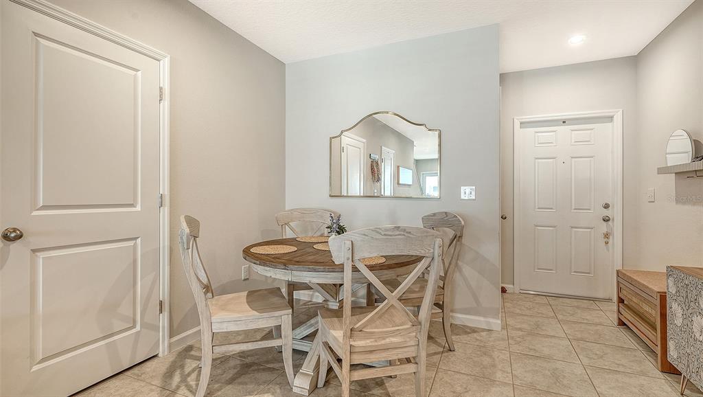 A dining area features a round wooden table with four chairs, a mirror, and tile flooring — 14147 CRIMSON AVENUE, BRADENTON, FL