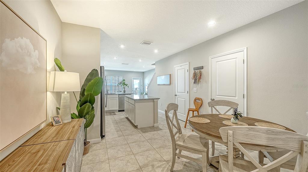 A dining area with a wooden table and chairs leads into a kitchen with an island — 14147 CRIMSON AVENUE, BRADENTON, FL