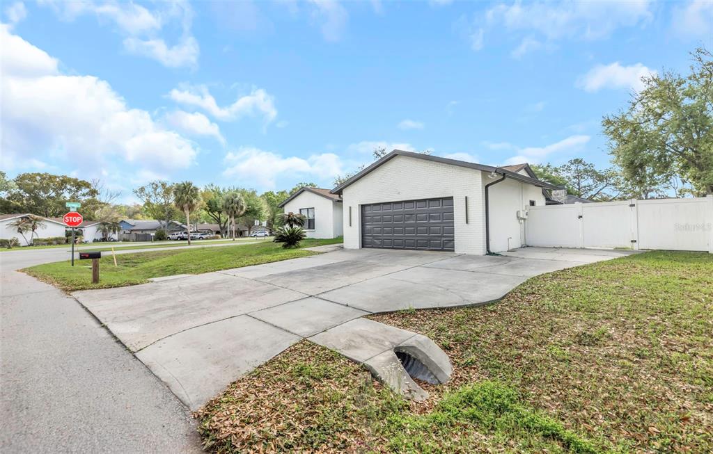 A white brick house with a dark garage door and a concrete driveway — 4030 FIELDGREEN PLACE, LAND O LAKES, FL