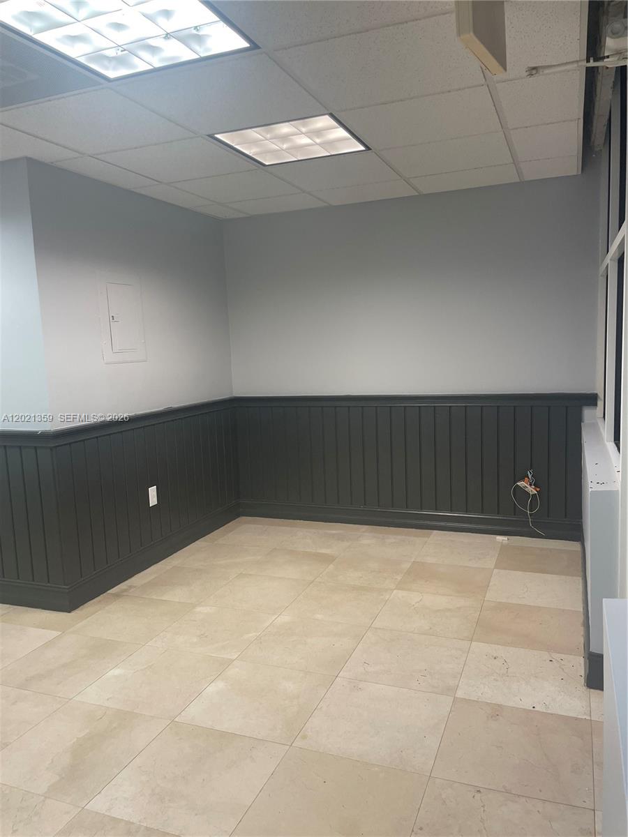 An empty office features light gray walls, dark wainscoting, and beige tile flooring — MIAMI, FL