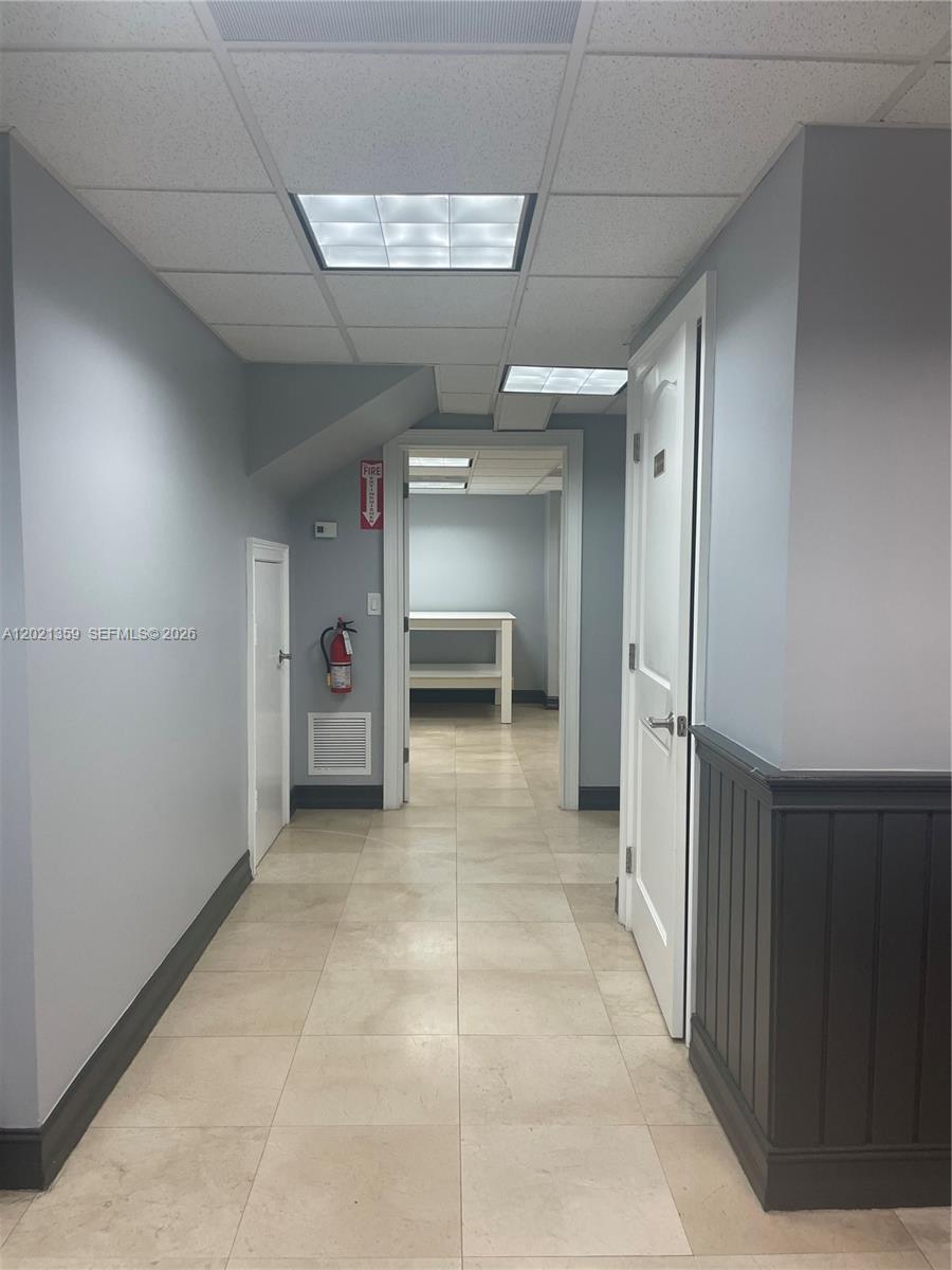 A hallway with light tile flooring, gray walls, and a white door leads to another room — MIAMI, FL