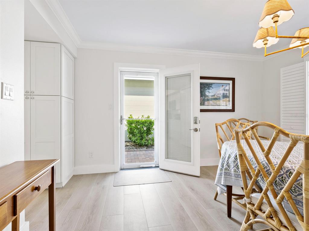 A dining area features light wood floors, white cabinetry, a glass door, and rattan chairs — 1214 MOONMIST CIRCLE UNIT S-01S, SARASOTA, FL