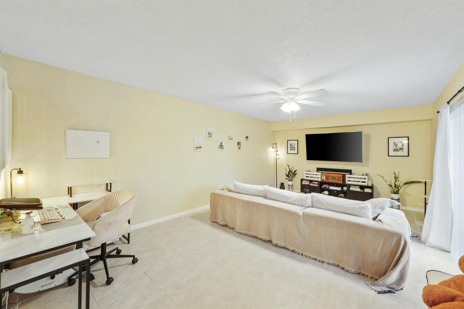 A living room features a beige sofa, a television on a media console, and a desk — 5110 51st Way, West Palm Beach FL 33409, WEST PALM BEACH, FL