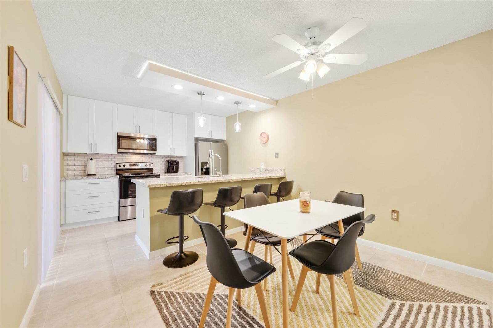 A kitchen with white cabinets and a breakfast bar opens into a dining area — 5110 51st Way, West Palm Beach FL 33409, WEST PALM BEACH, FL
