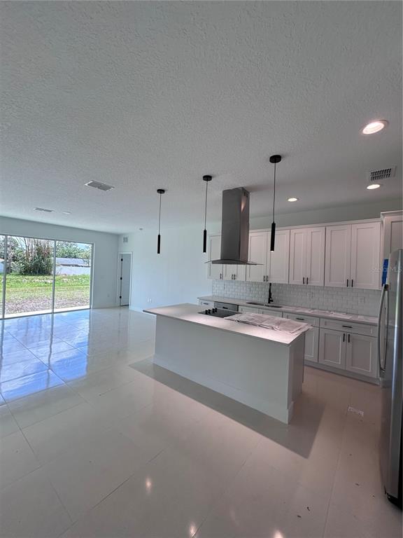 A modern kitchen features white cabinetry, a central island, and stainless steel appliances — 286 CATALONIA AVENUE NW, PALM BAY, FL