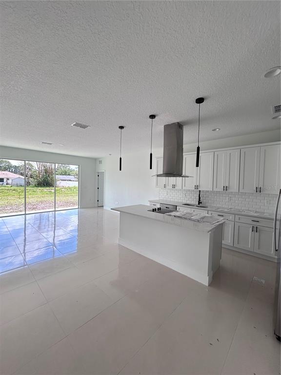 A modern kitchen features white cabinetry, a central island, and tile flooring in an open space — 286 CATALONIA AVENUE NW, PALM BAY, FL