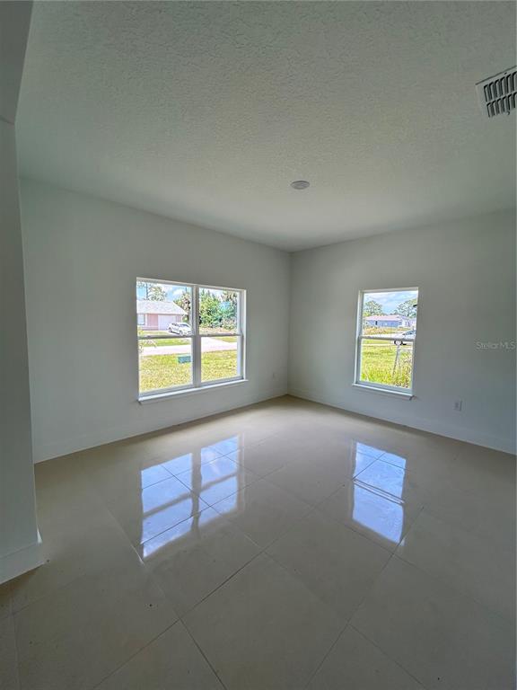 An empty room with white walls, large windows, and light-colored tile flooring — 286 CATALONIA AVENUE NW, PALM BAY, FL