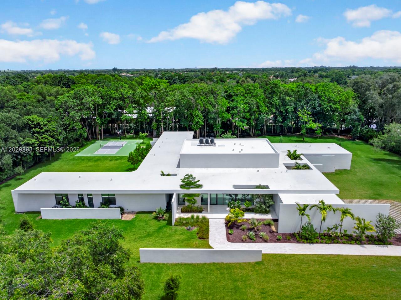 An aerial view of a modern white flat-roofed house with a backyard sports court — 5671 SW 130th Ave, Southwest Ranches FL 33330, SOUTHWEST RANCHES, FL