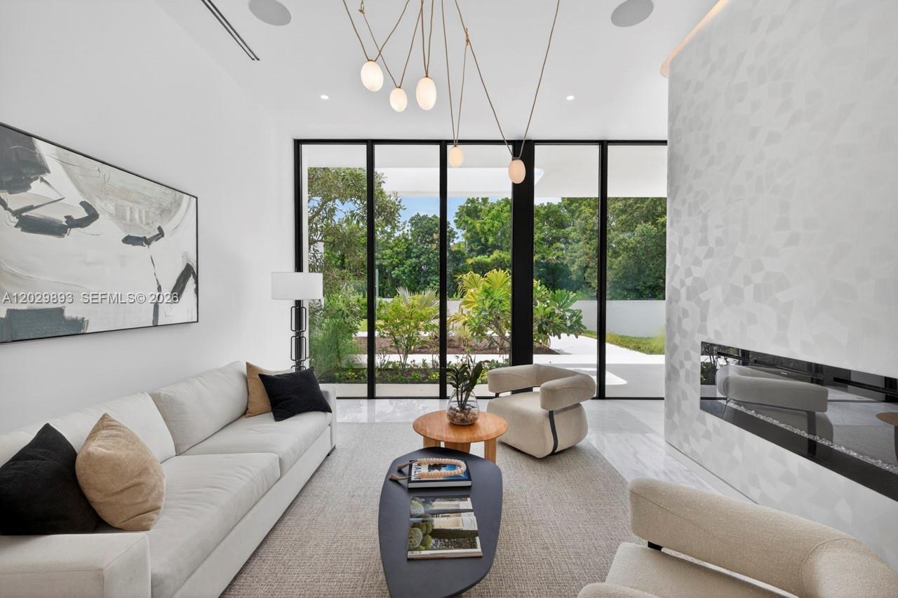 A modern living room features a fireplace, floor-to-ceiling windows, and contemporary furniture — 5671 SW 130th Ave, Southwest Ranches FL 33330, SOUTHWEST RANCHES, FL