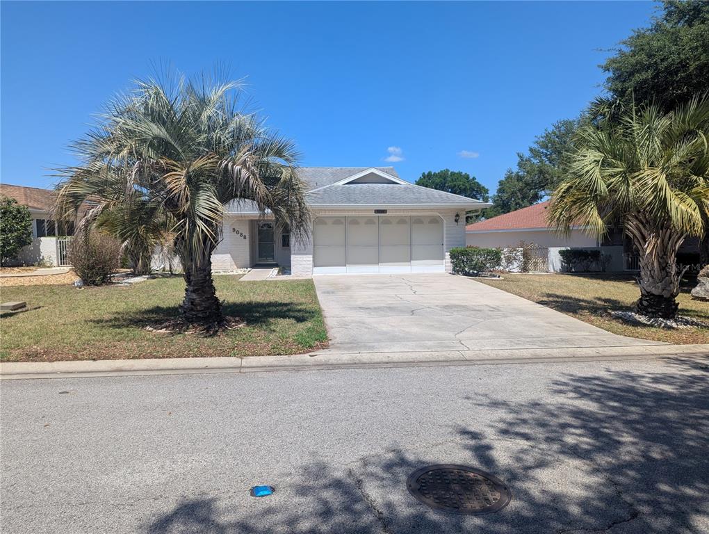 A single-story house with a white brick facade, two-car garage, and two palm trees — 9088 SW 91ST TERRACE, OCALA, FL