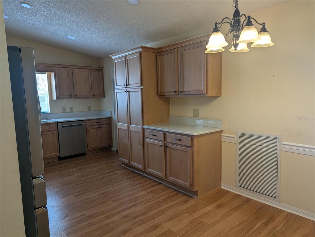 A kitchen with light wood cabinets, stainless steel appliances, and a dining area chandelier — 9088 SW 91ST TERRACE, OCALA, FL