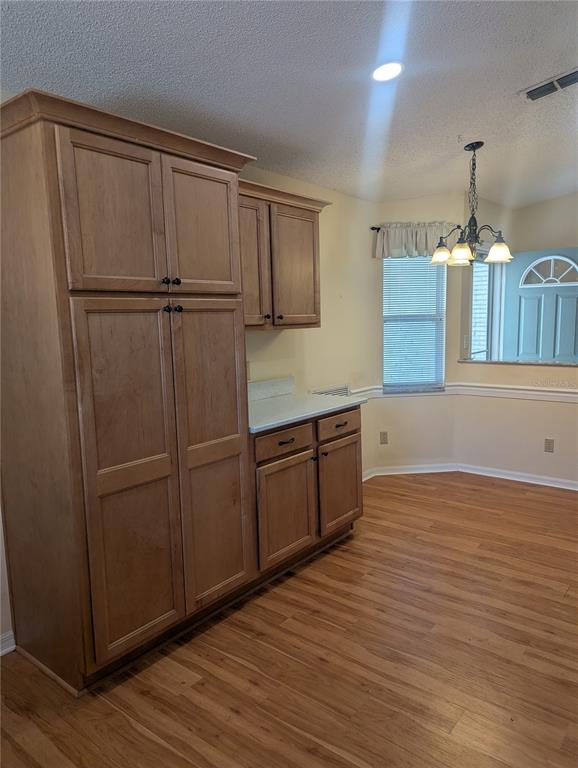 A kitchen area features light wood cabinets, a white countertop, and wood-look flooring — 9088 SW 91ST TERRACE, OCALA, FL