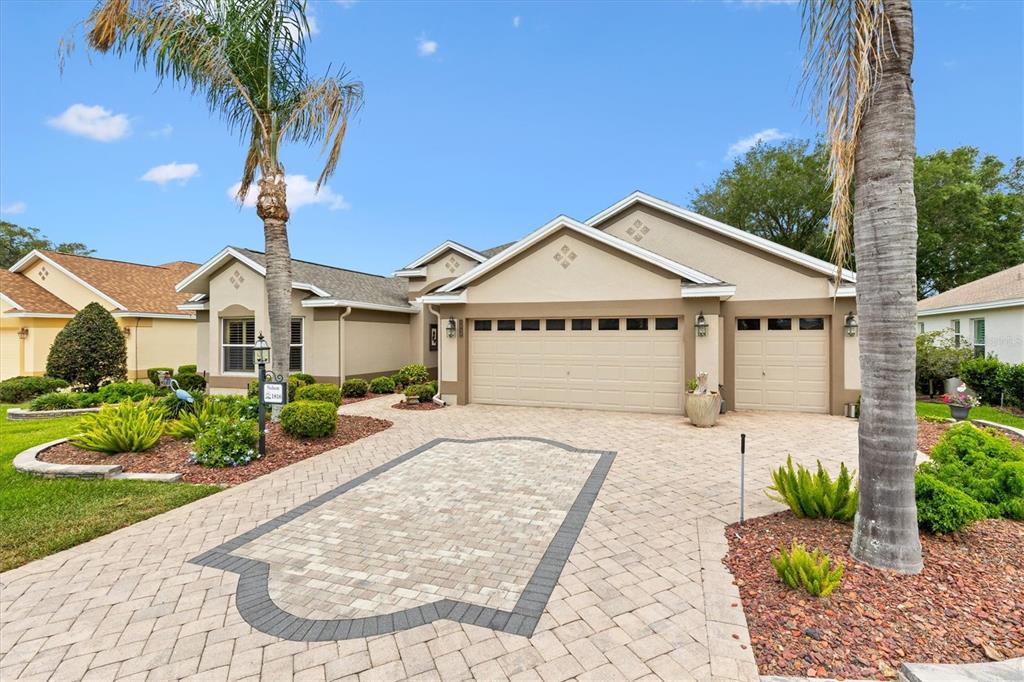 An aerial view shows a tan suburban house with a paved driveway and palm trees — 1816 BLYTHEWOOD LOOP, THE VILLAGES, FL
