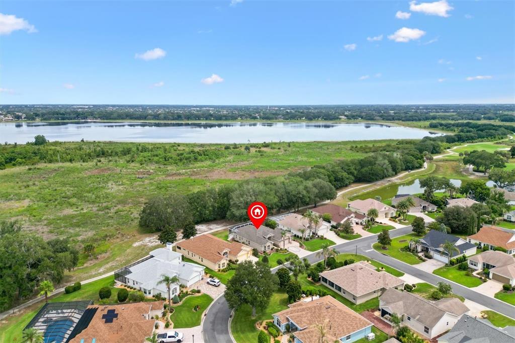 A screened-in patio features outdoor furniture, potted plants, and a view of a grassy field — 1816 BLYTHEWOOD LOOP, THE VILLAGES, FL