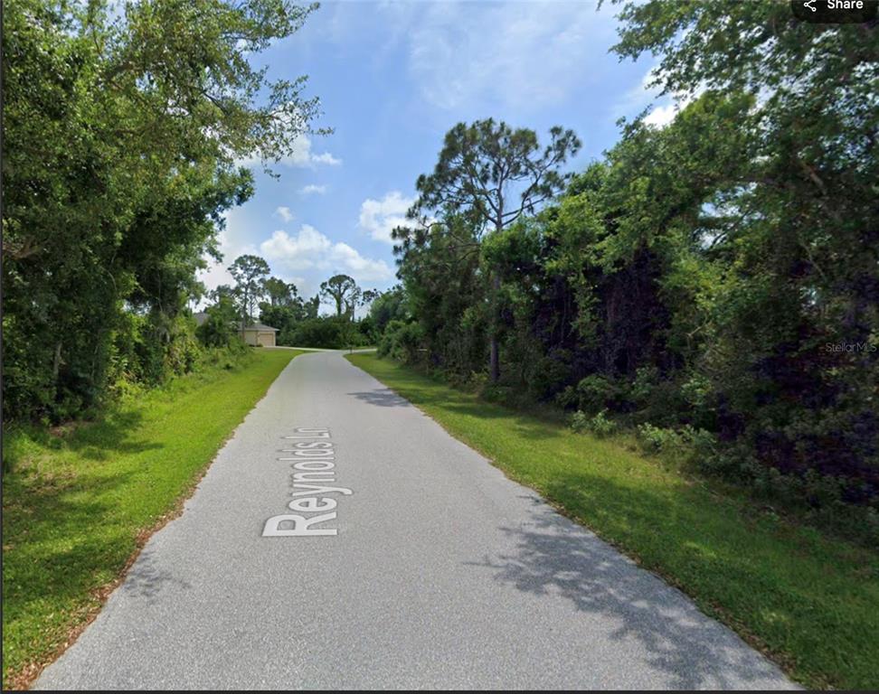 A paved road leads through a wooded area toward a house in the distance — 4193 REYNOLDS LANE, PORT CHARLOTTE, FL