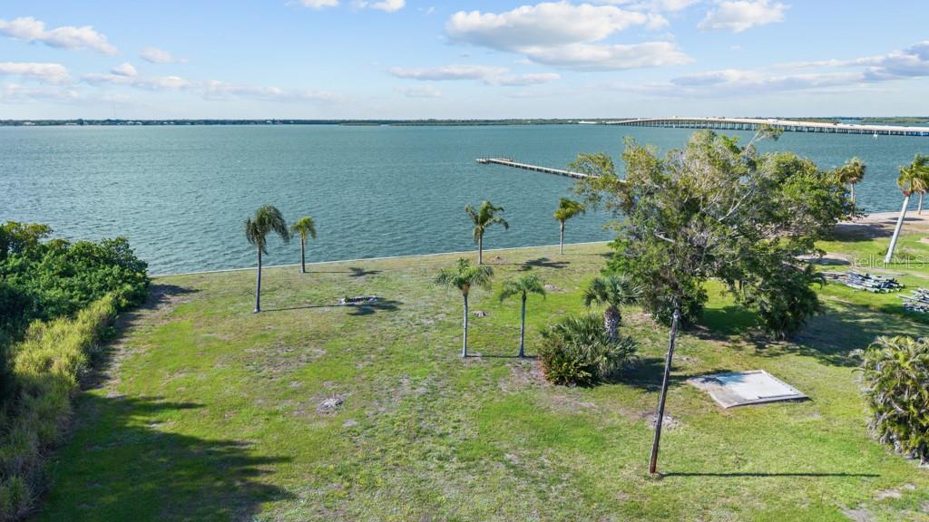 An aerial view of a grassy waterfront lot with several palm trees and a wooden pier — 26014 SHORE DRIVE, PUNTA GORDA, FL