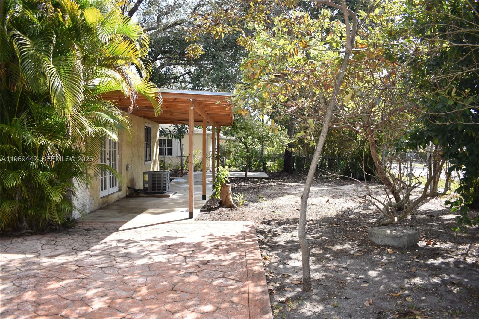 A paved patio sits beside a house with a wooden porch and a large yard — 14015 NE 11th Ave, North Miami FL 33161, NORTH MIAMI, FL