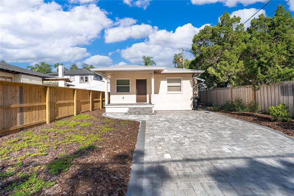 A small, light-colored house features a paved driveway, a front porch, and a wooden fence — 623 FLORIDA STREET, ORLANDO, FL