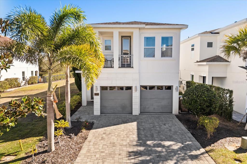 A two-story house with a paved driveway, two garage doors, and a second-floor balcony — 1113 CASTLE PINES COURT, REUNION, FL