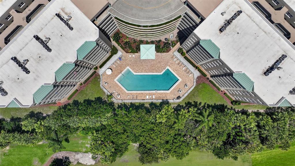 An aerial view shows a swimming pool nestled between two large residential buildings with landscaping — 4 OCEANS WEST BOULEVARD UNIT 207A, DAYTONA BEACH, FL