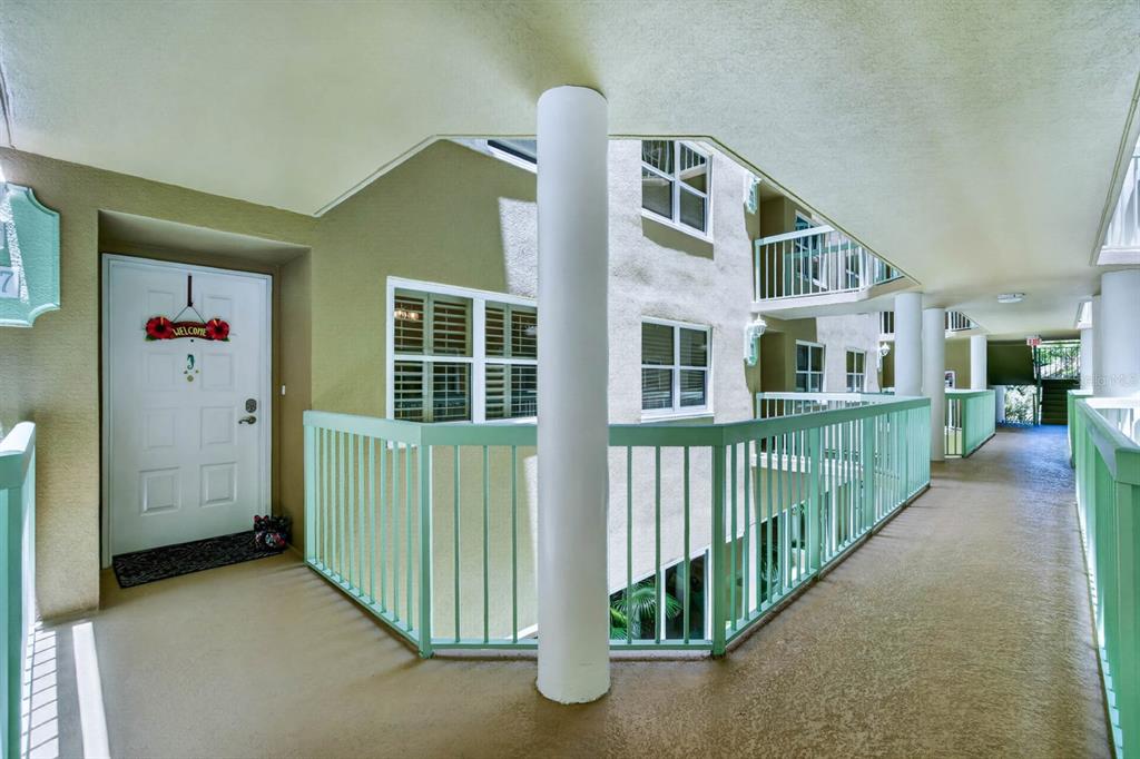 An outdoor apartment building walkway with a white door, green railings, and a central pillar — 4 OCEANS WEST BOULEVARD UNIT 207A, DAYTONA BEACH, FL