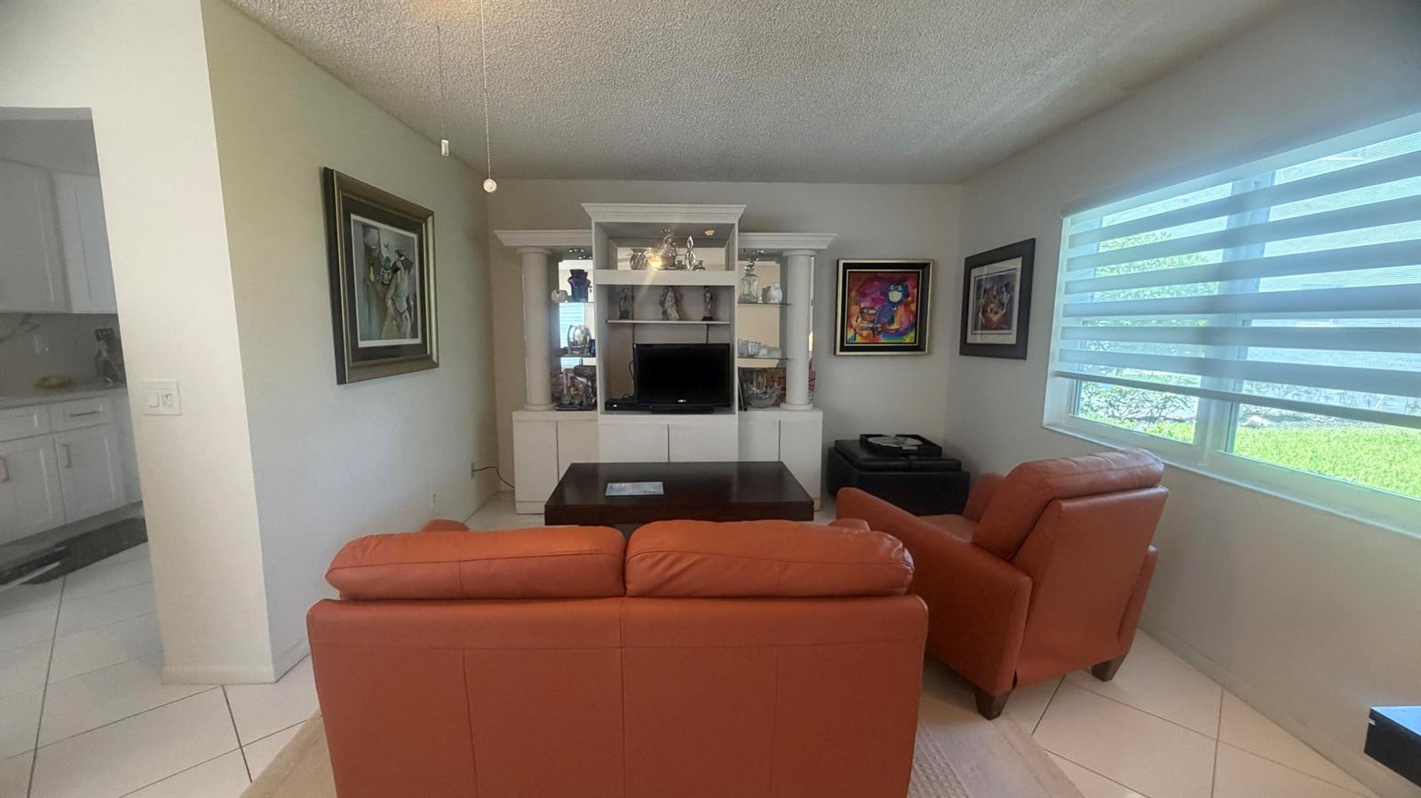 A living room features orange leather seating, a white entertainment center, and tile flooring — 930 Normandy, Delray Beach FL 33484, DELRAY BEACH, FL