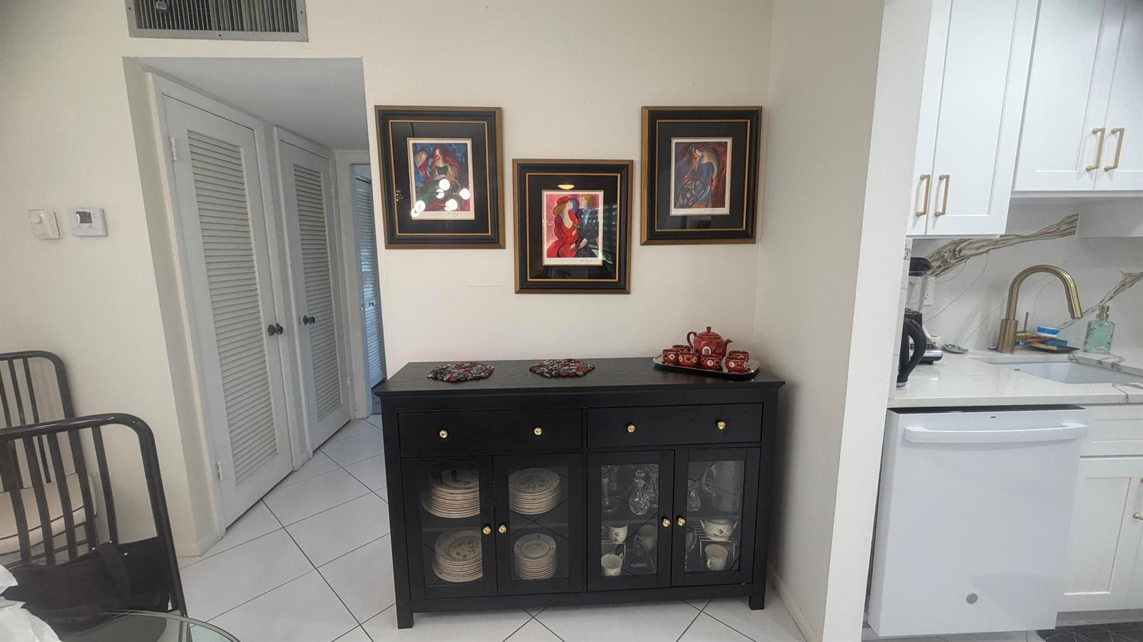 A black sideboard with glass-front cabinets sits against a wall beneath three framed pictures — 930 Normandy, Delray Beach FL 33484, DELRAY BEACH, FL