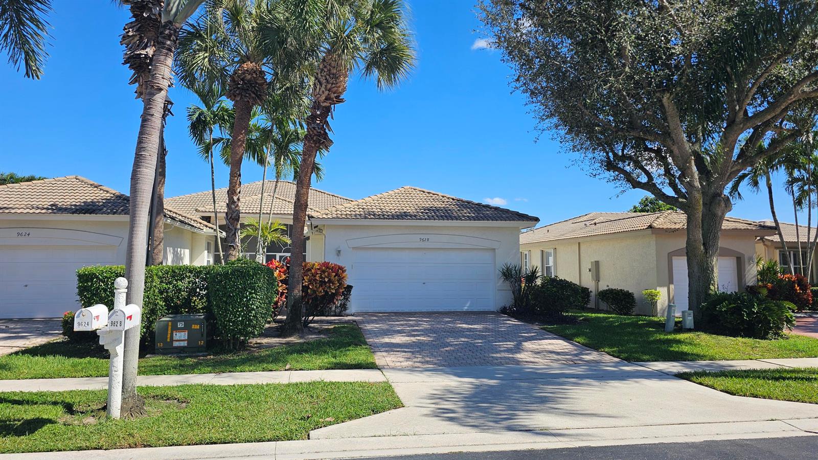 A street view of two single-story suburban houses with tile roofs and paved driveways — 9628 Crescent View Drive N, Boynton Beach FL 33437, BOYNTON BEACH, FL