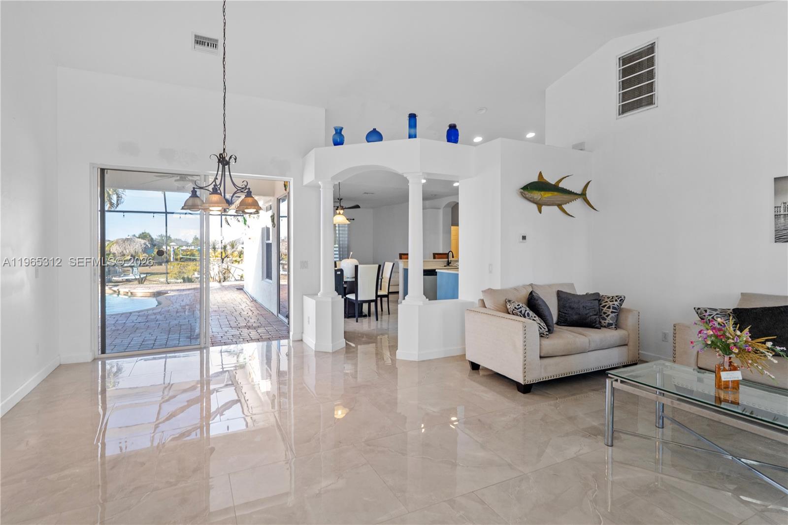 A bright living room features white walls, large glossy floor tiles, and a front entryway — 2025 NW 7th ter, Cape Coral FL 33993, CAPE CORAL, FL