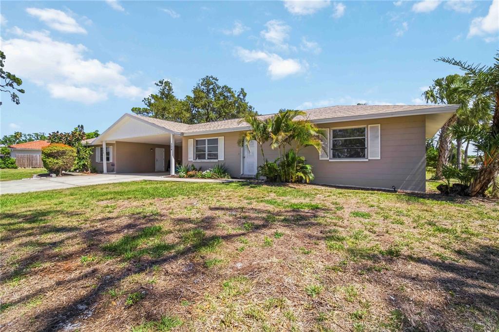 A single-story house with a tan exterior, a carport, and a grassy front yard — 304 LANTANA AVENUE, SARASOTA, FL
