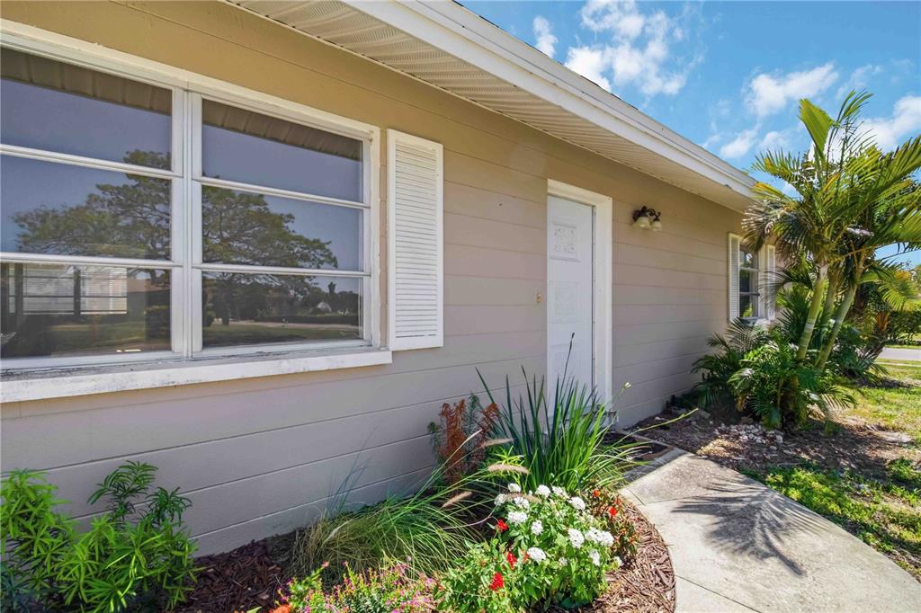 A tan house exterior features a white front door, shuttered windows, and a landscaped walkway — 304 LANTANA AVENUE, SARASOTA, FL