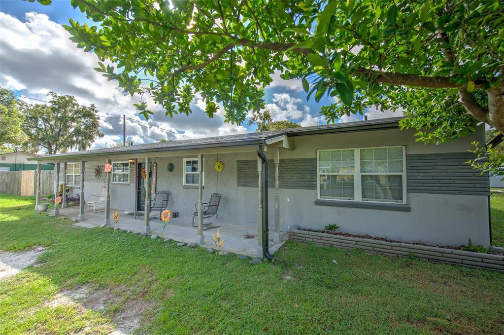 A single-story house with a covered front porch, gray siding, and a large front lawn — 38708 9TH AVENUE, ZEPHYRHILLS, FL