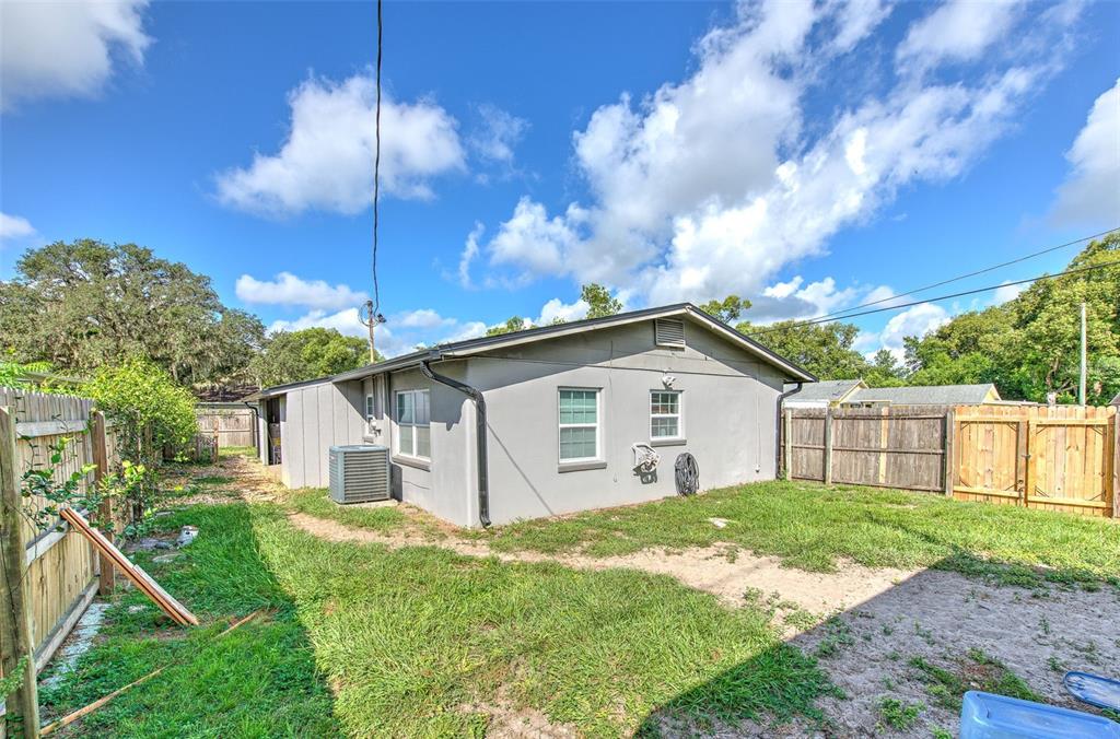 The exterior of a gray house features a fenced backyard with a central air unit — 38708 9TH AVENUE, ZEPHYRHILLS, FL