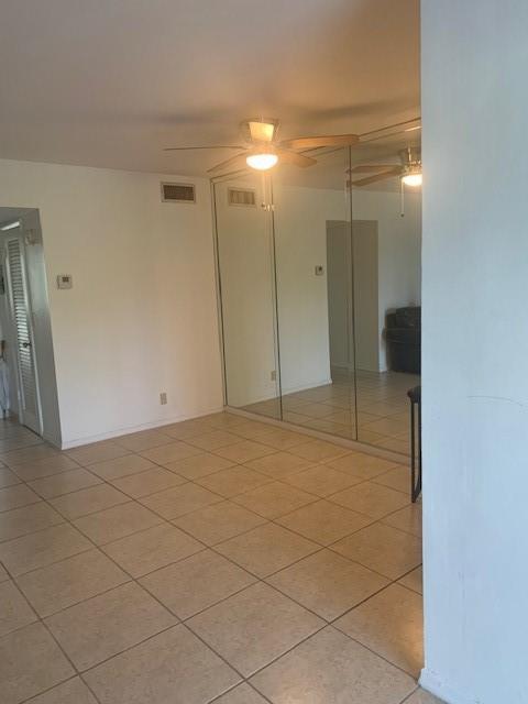 A room with light-colored tile flooring, a ceiling fan, and a wall of mirrored closet doors — 270 Layne Boulevard # 308, Hallandale Beach FL 33009, HALLANDALE BEACH, FL