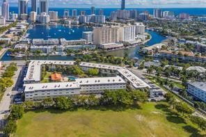 An aerial view shows a multi-story apartment complex situated near a bay and city skyline — 270 Layne Boulevard # 308, Hallandale Beach FL 33009, HALLANDALE BEACH, FL