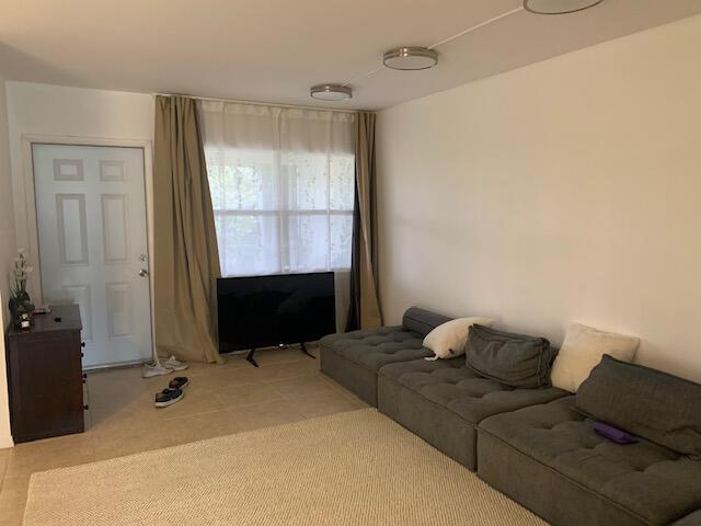 A living room features a grey modular sofa, a television, and a beige area rug — 270 Layne Boulevard # 308, Hallandale Beach FL 33009, HALLANDALE BEACH, FL