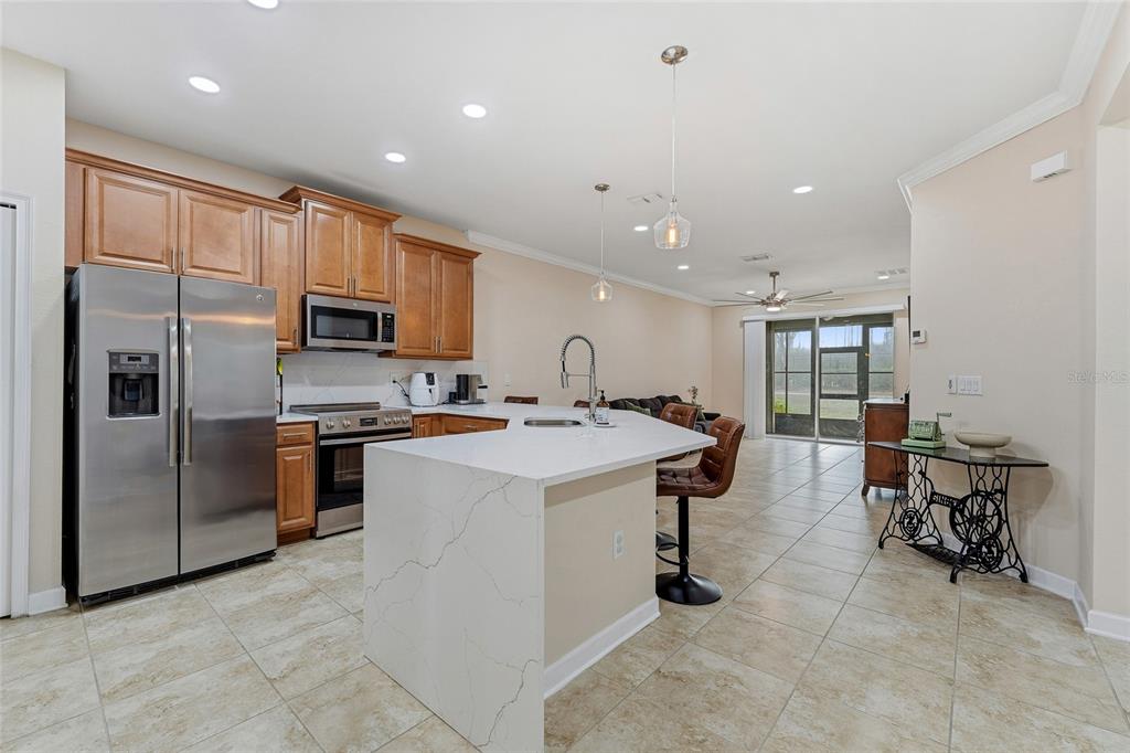A kitchen with wood cabinets, stainless steel appliances, and a white quartz-topped island — 3550 FAIRWATERS COURT UNIT #C, CLERMONT, FL