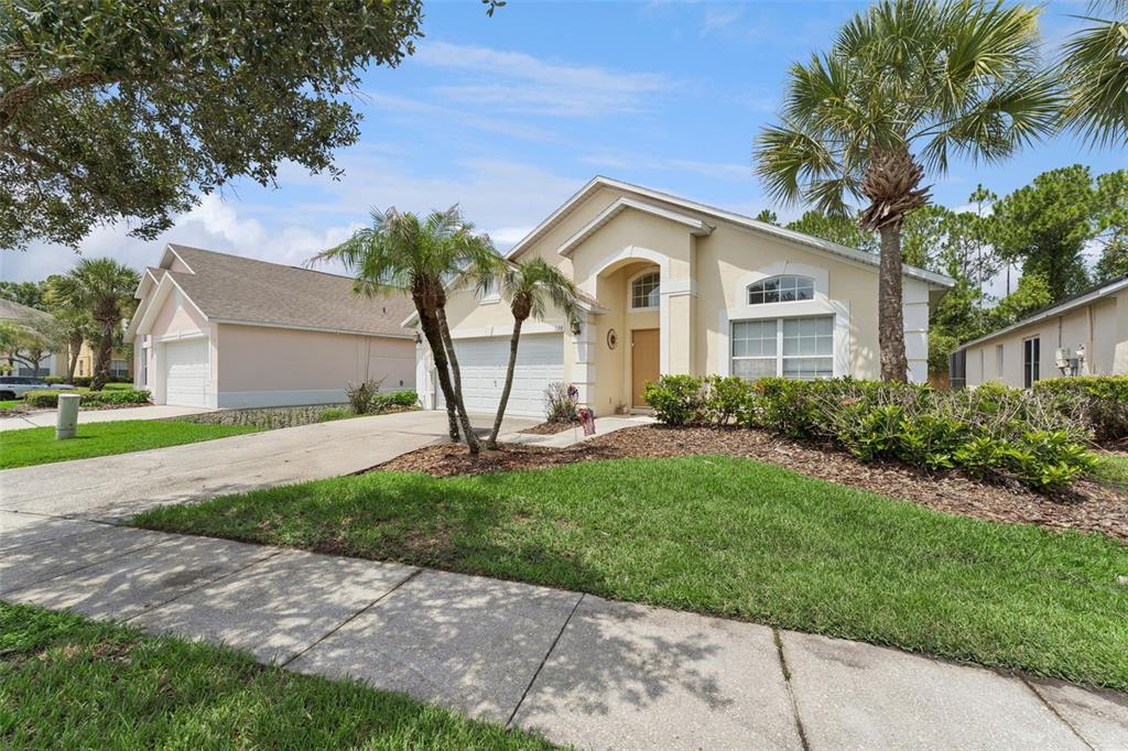 A single-story beige house with a two-car garage and palm trees in the front yard — 126 MADIERA BEACH BLVD, KISSIMMEE, FL