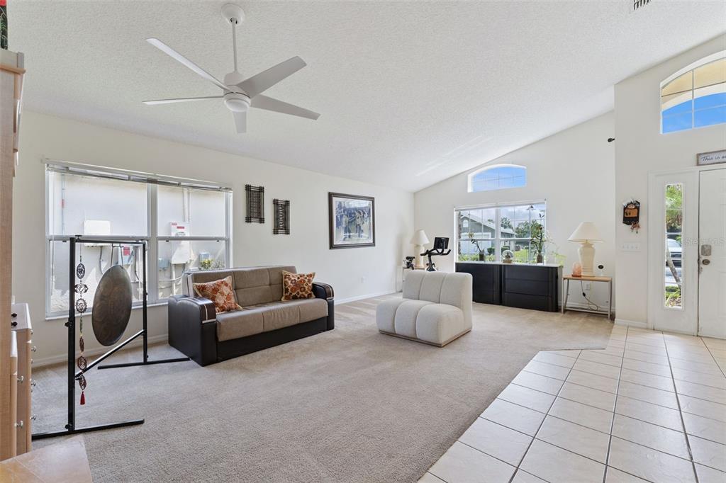 A living room features a beige sofa, a white armchair, a ceiling fan, and carpeted floors — 126 MADIERA BEACH BLVD, KISSIMMEE, FL