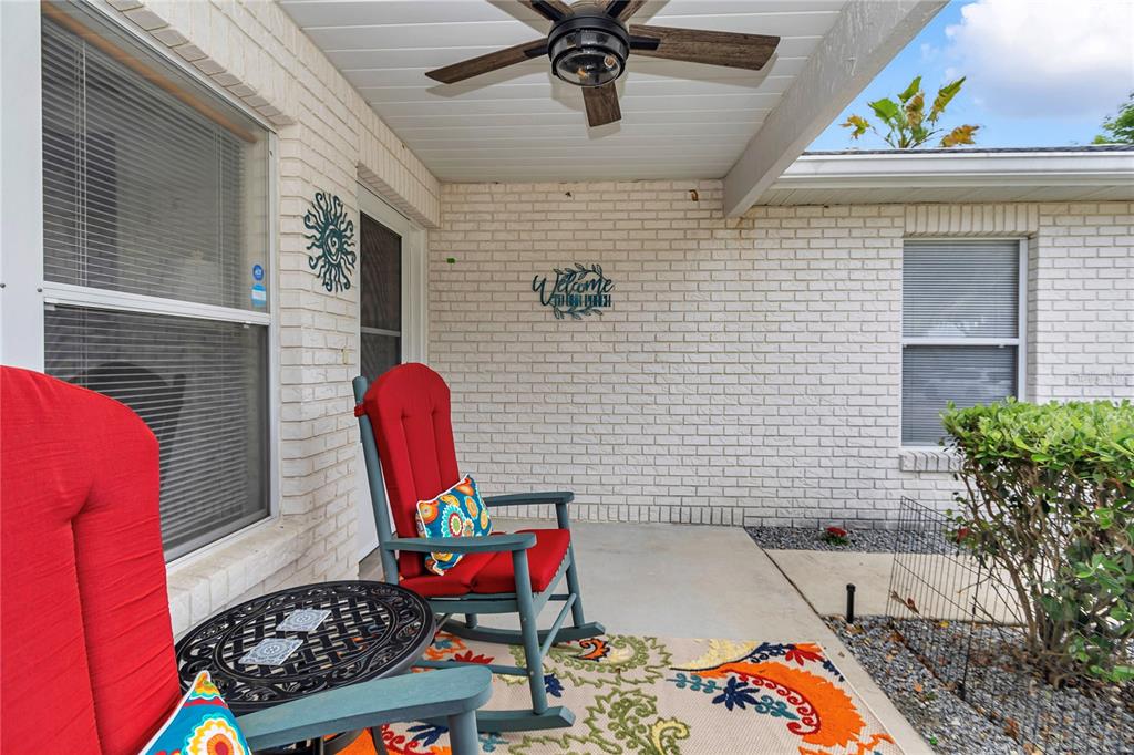 A covered brick porch features two red rocking chairs, a small table, and a ceiling fan — 9185 SW 90TH STREET, OCALA, FL