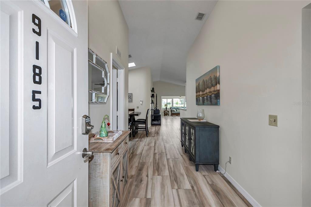 An entryway leads into a living area with wood-look tile flooring and vaulted ceilings — 9185 SW 90TH STREET, OCALA, FL